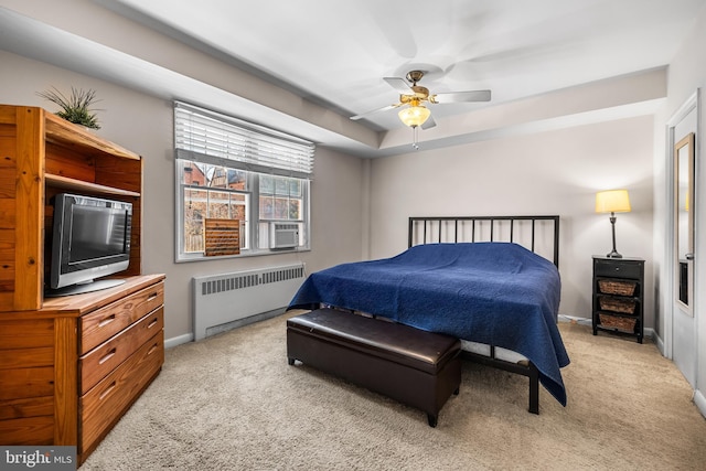 carpeted bedroom featuring ceiling fan, radiator, a tray ceiling, and baseboards