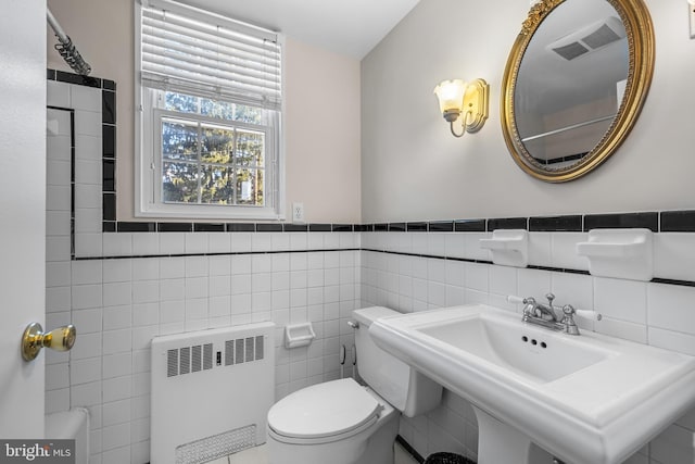 bathroom with radiator, visible vents, a sink, tile walls, and toilet