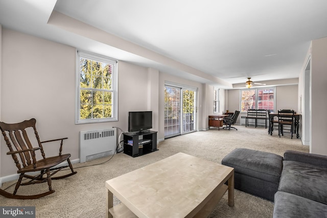 carpeted living area with baseboards, radiator, and a ceiling fan