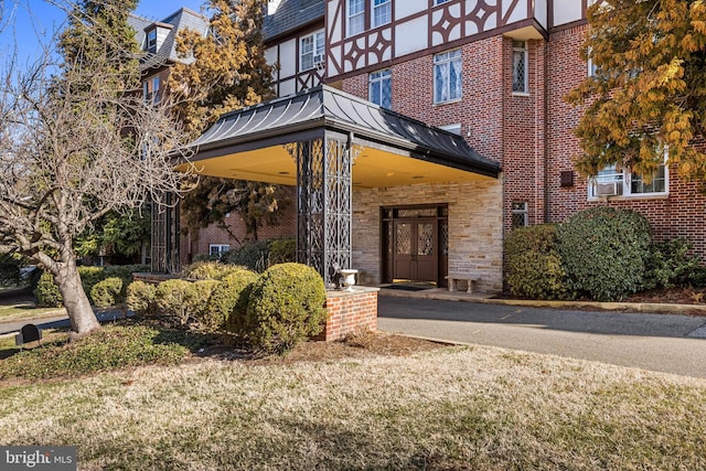 doorway to property with metal roof, stone siding, brick siding, and a standing seam roof