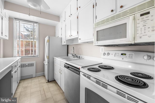 kitchen with light countertops, radiator heating unit, white cabinets, white appliances, and a sink