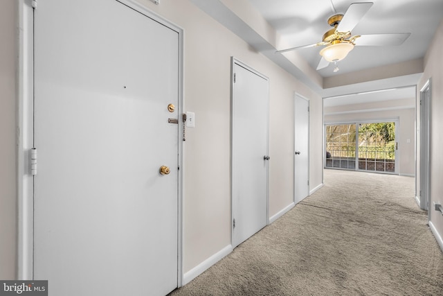 corridor featuring baseboards and carpet flooring