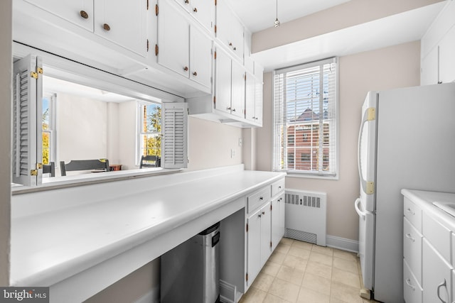 kitchen featuring white cabinets, radiator, light countertops, and freestanding refrigerator