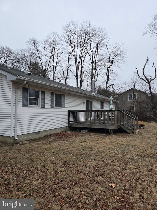 rear view of property featuring a wooden deck and a lawn