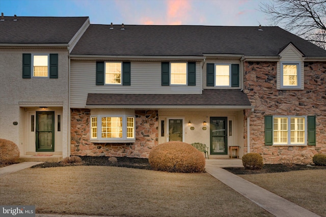 multi unit property featuring stucco siding, roof with shingles, and stone siding