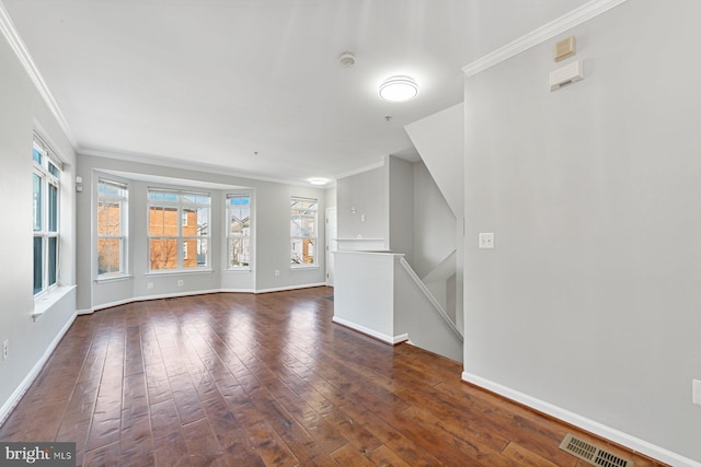 empty room featuring dark wood-style floors, visible vents, crown molding, and baseboards