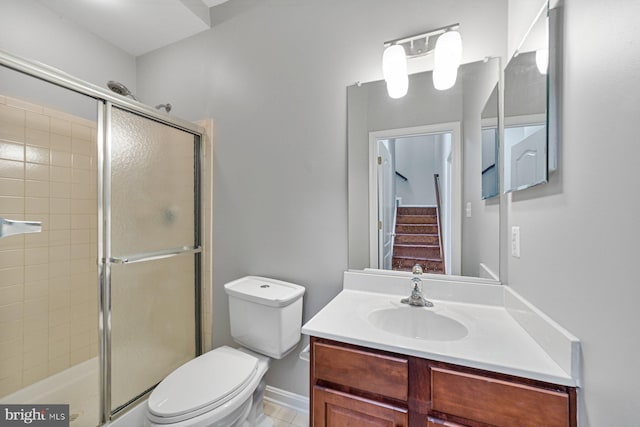 bathroom featuring baseboards, a shower stall, toilet, and vanity