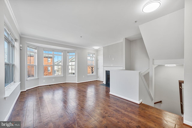 unfurnished living room with dark wood-style floors, a fireplace with flush hearth, baseboards, and crown molding