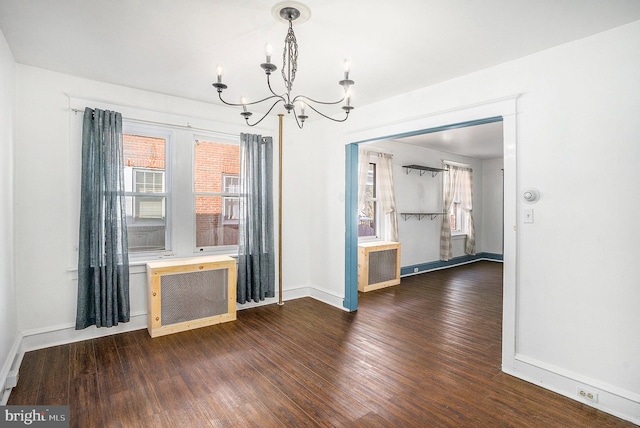 unfurnished dining area featuring radiator, plenty of natural light, dark wood-type flooring, and a chandelier