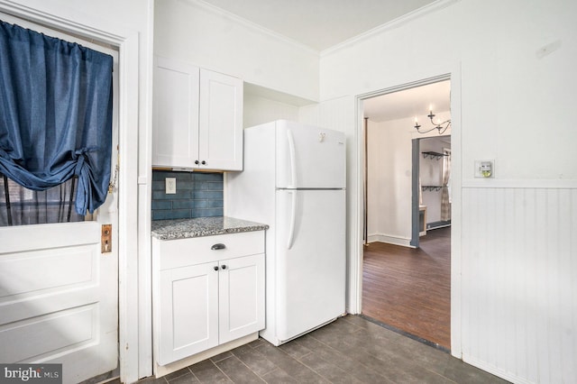 kitchen with stone counters, white refrigerator, dark hardwood / wood-style flooring, white cabinets, and ornamental molding