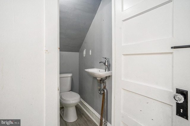 bathroom featuring hardwood / wood-style flooring, sink, vaulted ceiling, and toilet