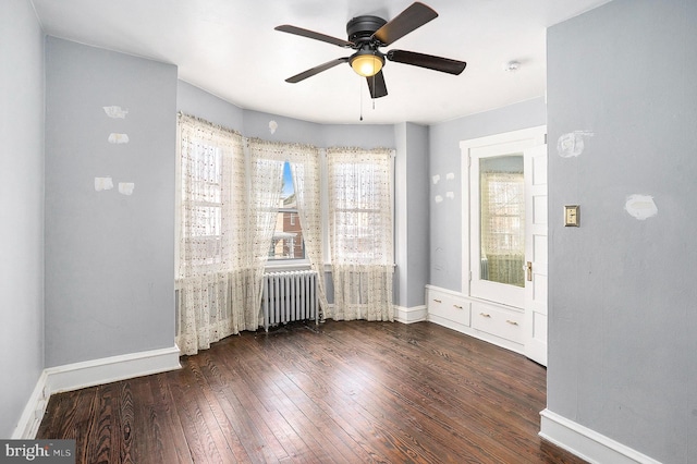 spare room featuring radiator heating unit, ceiling fan, plenty of natural light, and dark hardwood / wood-style flooring