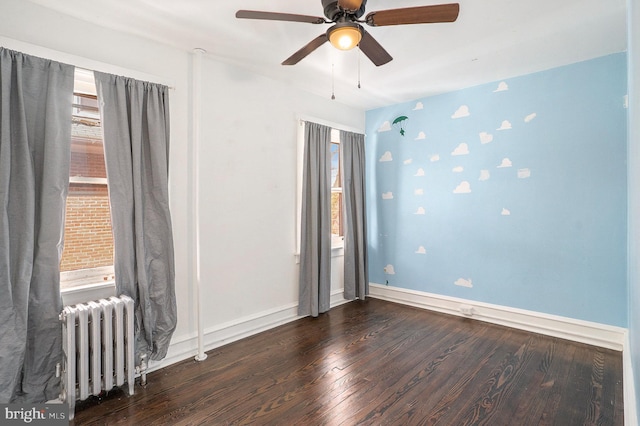 empty room featuring radiator, dark hardwood / wood-style floors, and ceiling fan