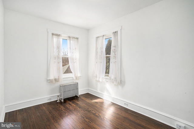 empty room with radiator heating unit and hardwood / wood-style flooring