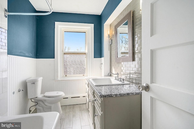 bathroom with plenty of natural light, vanity, toilet, and a baseboard heating unit