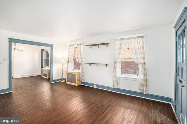 interior space with dark hardwood / wood-style floors, a chandelier, and radiator heating unit