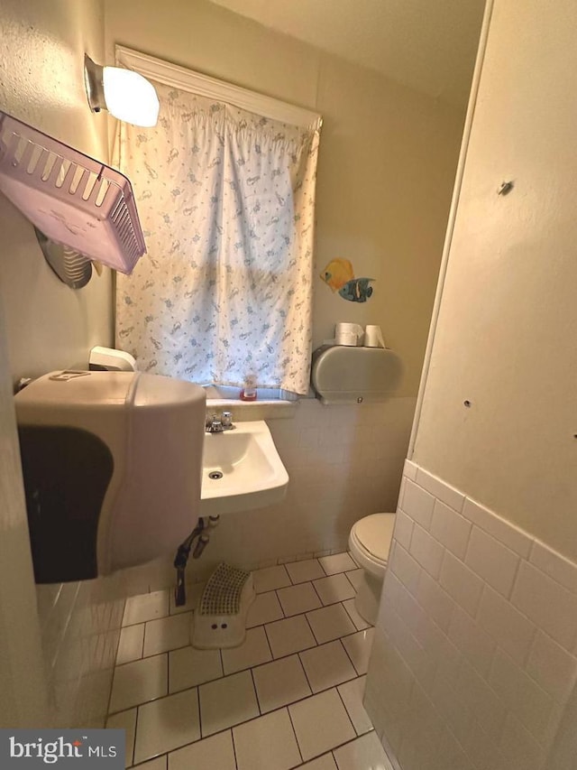 bathroom featuring sink, toilet, tile patterned flooring, and tile walls