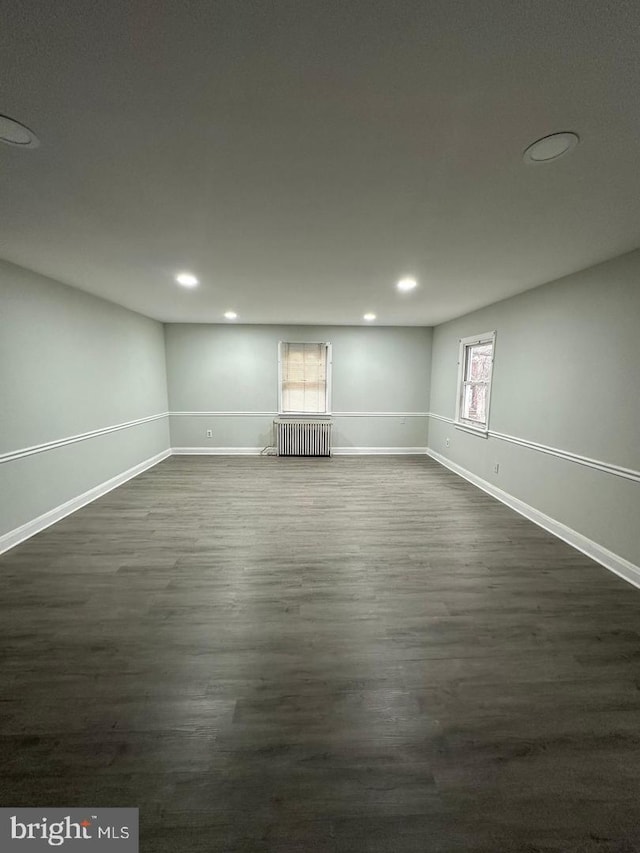 basement with dark hardwood / wood-style flooring and radiator