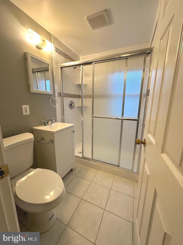 bathroom with tile patterned flooring, vanity, a shower with door, and toilet