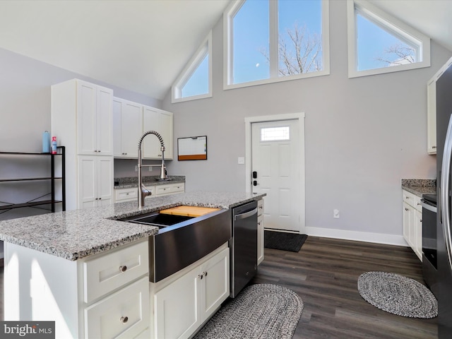 kitchen featuring white cabinetry, a center island with sink, sink, stainless steel dishwasher, and light stone counters