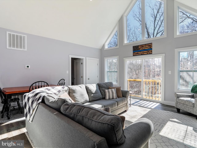 living room with high vaulted ceiling, dark wood-type flooring, and a healthy amount of sunlight