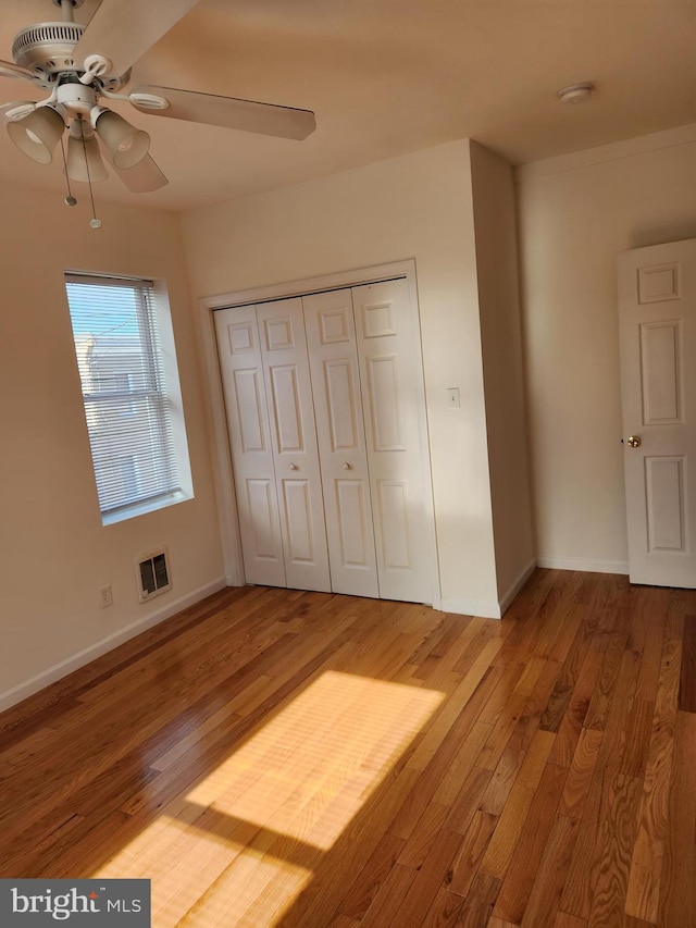 unfurnished bedroom featuring wood-type flooring, a closet, and ceiling fan