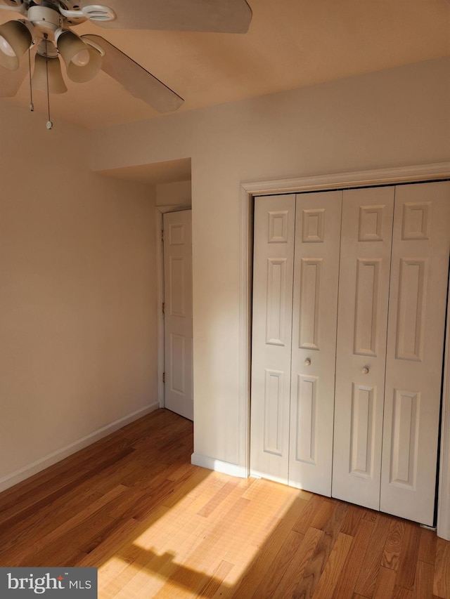 unfurnished bedroom with ceiling fan, light wood-type flooring, and a closet