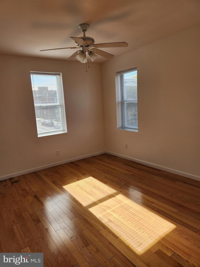 empty room with hardwood / wood-style flooring, a wealth of natural light, and ceiling fan