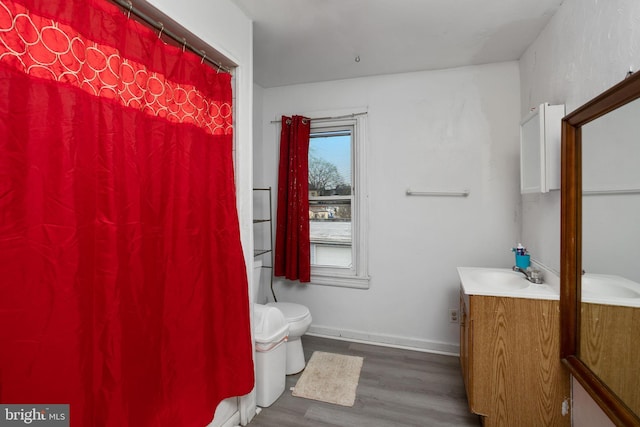 bathroom with toilet, vanity, and hardwood / wood-style floors