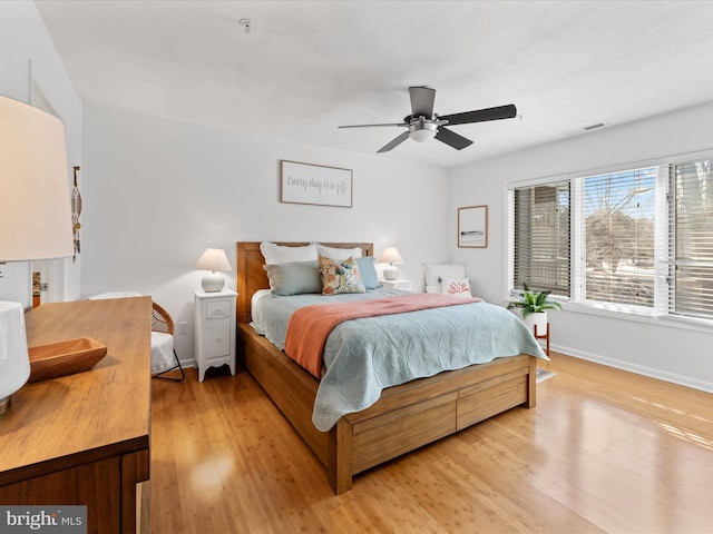 bedroom featuring light wood-style flooring, visible vents, baseboards, and a ceiling fan