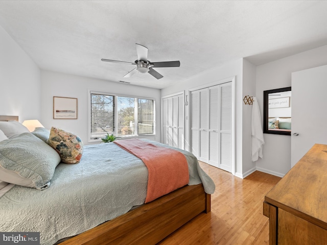 bedroom featuring multiple closets, light wood-type flooring, baseboards, and a ceiling fan