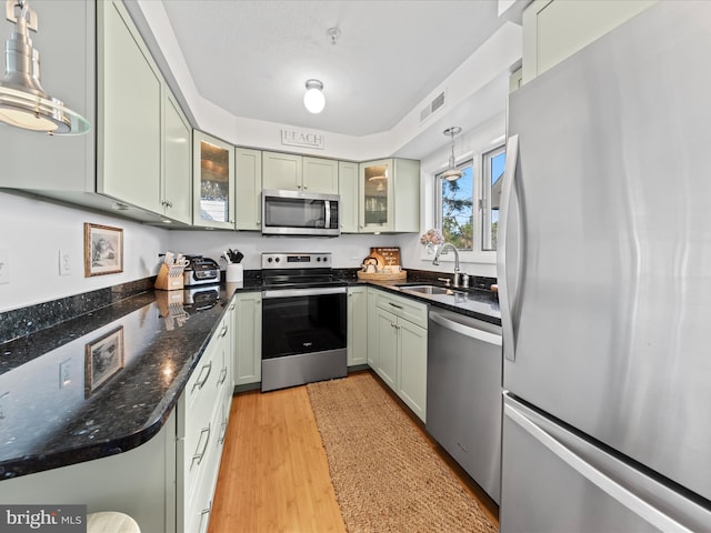 kitchen with light wood finished floors, visible vents, hanging light fixtures, stainless steel appliances, and a sink