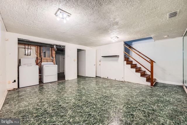 basement with a textured ceiling and washing machine and clothes dryer