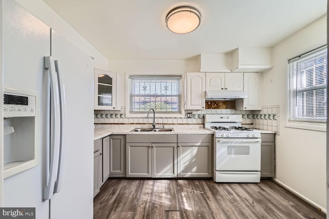 kitchen with sink, white appliances, dark wood-type flooring, backsplash, and white cabinets