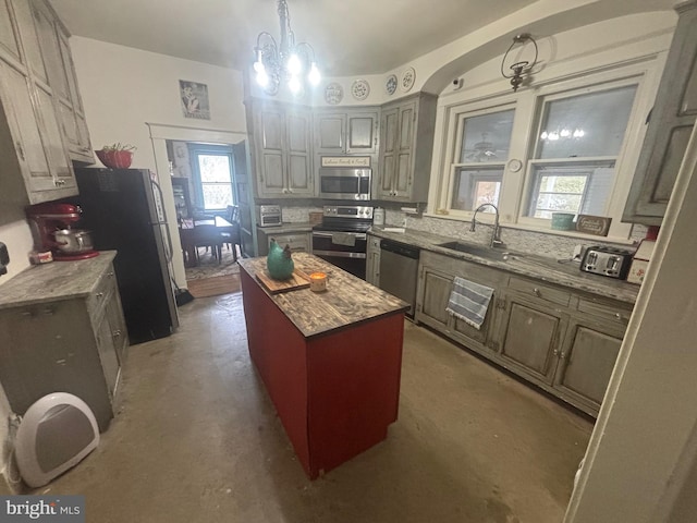 kitchen with a kitchen island, pendant lighting, sink, stainless steel appliances, and an inviting chandelier