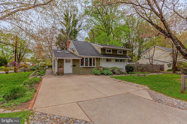 view of front of property featuring roof mounted solar panels, a front yard, a chimney, and fence