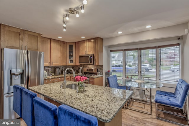 kitchen featuring recessed lighting, a sink, glass insert cabinets, light stone counters, and appliances with stainless steel finishes