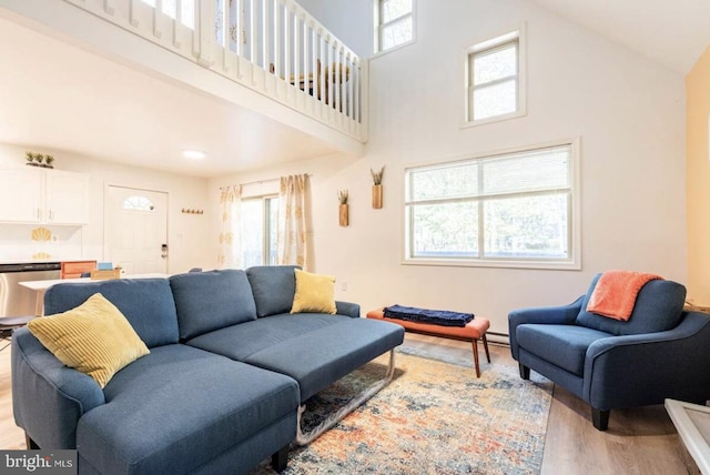 living room with light hardwood / wood-style floors, a high ceiling, and a wealth of natural light