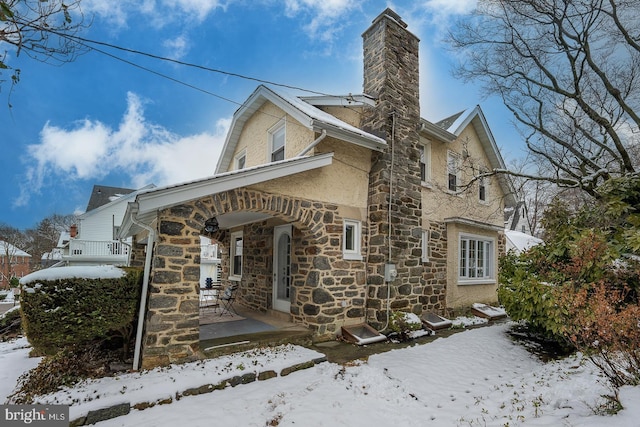 exterior space with stone siding, a chimney, and stucco siding