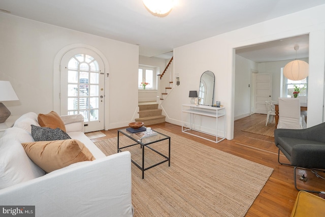 living room featuring light wood-style floors, baseboards, and stairway