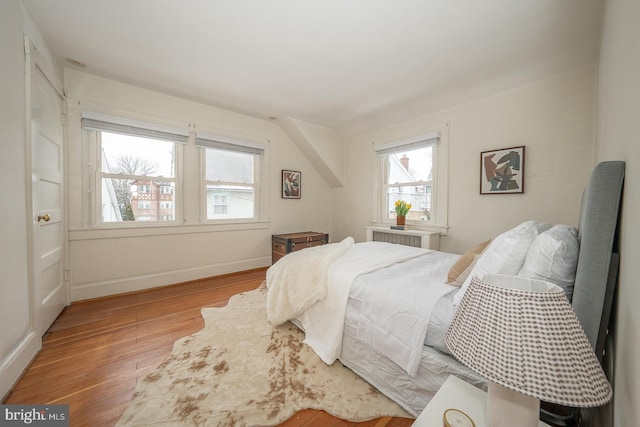 bedroom with radiator, baseboards, and wood finished floors