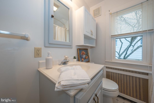 bathroom featuring toilet, vanity, visible vents, and radiator