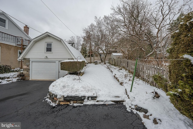 exterior space with a garage, fence, aphalt driveway, and a gambrel roof