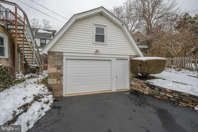 snow covered garage featuring fence