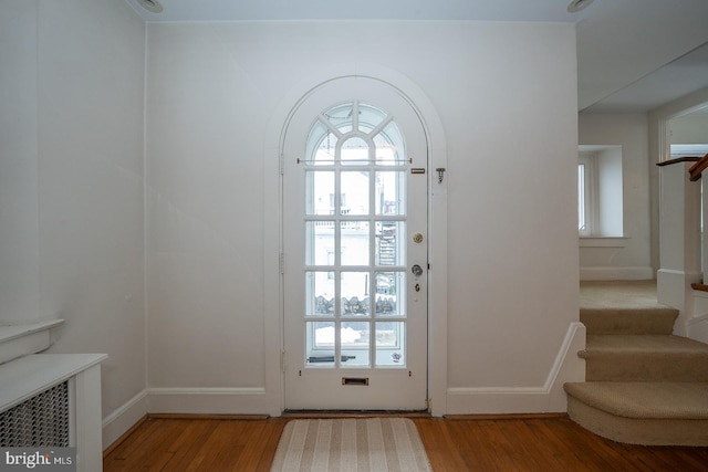 doorway with stairs, light wood-style flooring, and baseboards