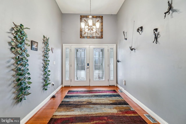 entrance foyer featuring a chandelier, french doors, baseboards, and wood finished floors