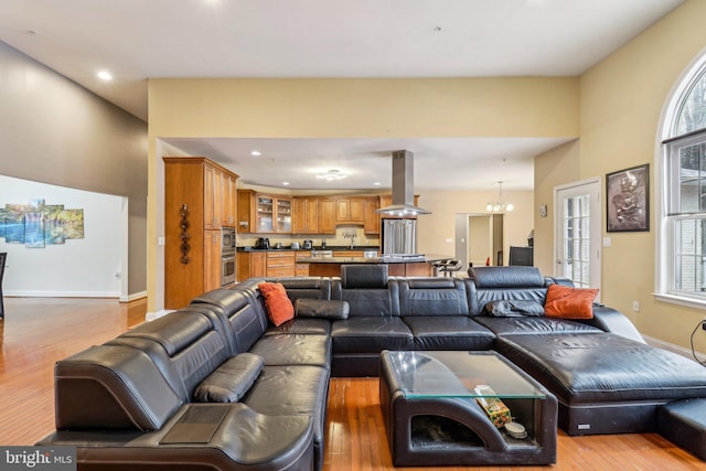 living room with an inviting chandelier, baseboards, wood finished floors, and recessed lighting