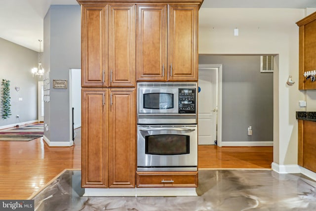 kitchen with visible vents, brown cabinetry, dark countertops, appliances with stainless steel finishes, and pendant lighting