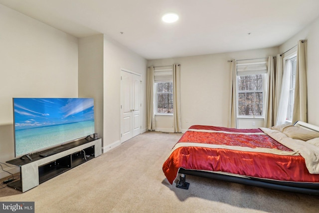 bedroom featuring light carpet, multiple windows, and baseboards