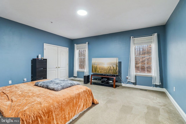 bedroom featuring light carpet, a closet, visible vents, and baseboards